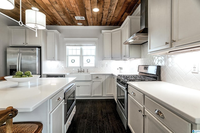 kitchen with wooden ceiling, a sink, visible vents, appliances with stainless steel finishes, and wall chimney exhaust hood