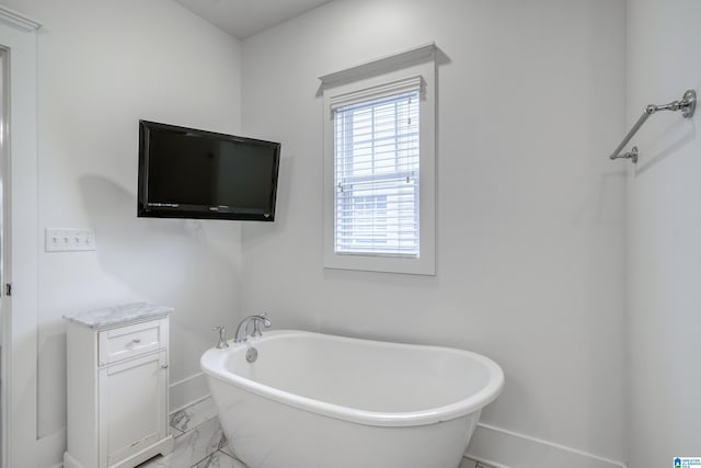 bathroom with marble finish floor, a soaking tub, and baseboards