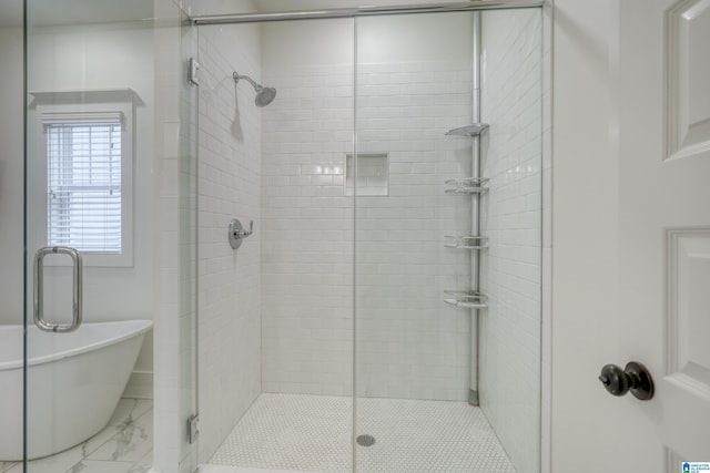 bathroom with marble finish floor, a freestanding tub, and a shower stall