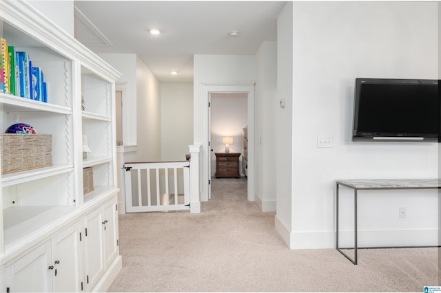 hallway featuring light carpet, an upstairs landing, and baseboards