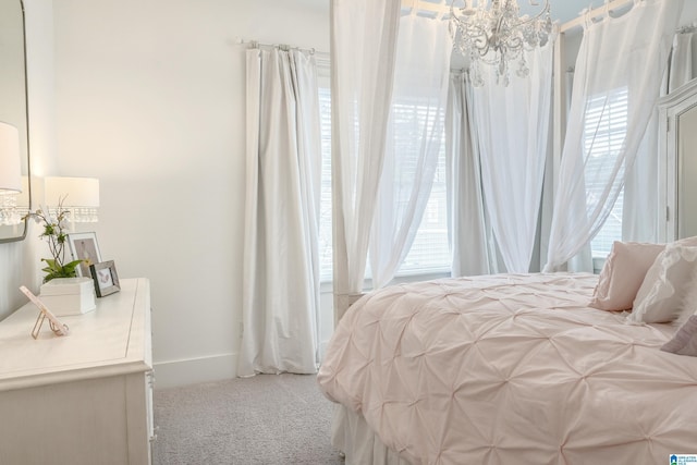 carpeted bedroom featuring baseboards and a notable chandelier