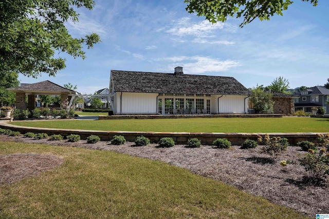 back of house with roof with shingles, a lawn, and a chimney