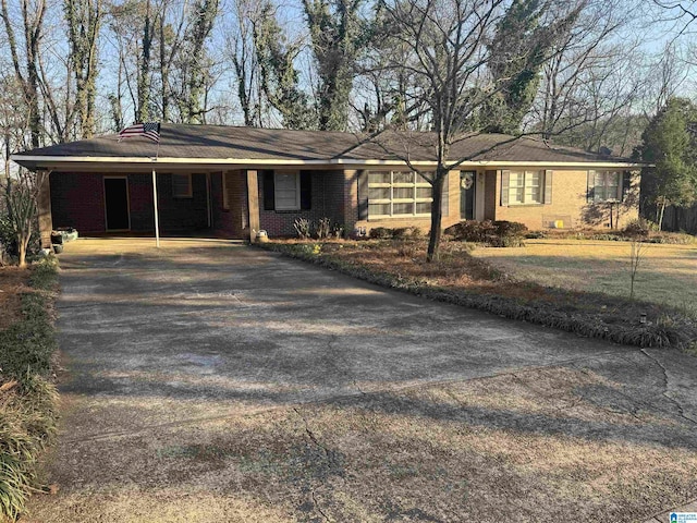 single story home featuring a carport, brick siding, and driveway