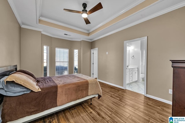 bedroom featuring crown molding, a raised ceiling, visible vents, wood finished floors, and baseboards