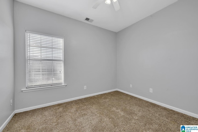 carpeted spare room with visible vents, ceiling fan, and baseboards