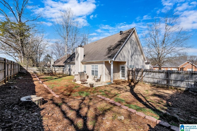 rear view of property featuring a patio area, a fenced backyard, a chimney, and a shingled roof