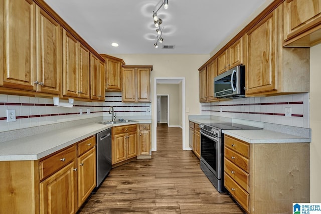 kitchen with light countertops, appliances with stainless steel finishes, dark wood-style flooring, and a sink