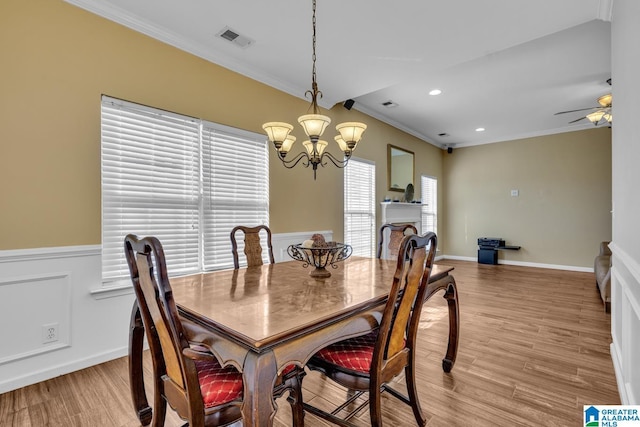 dining room featuring light wood-type flooring, visible vents, ornamental molding, and ceiling fan with notable chandelier