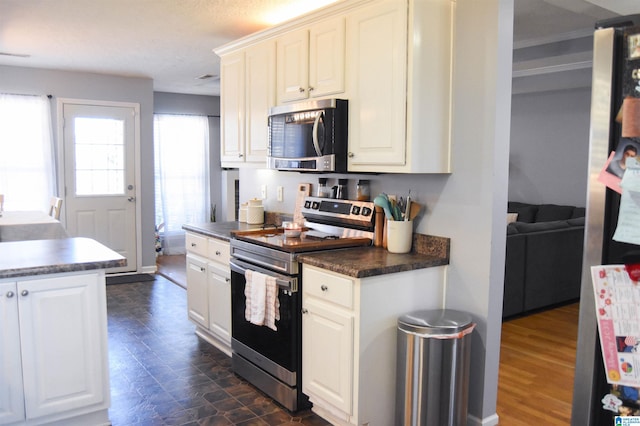 kitchen with dark countertops, baseboards, white cabinetry, and stainless steel appliances