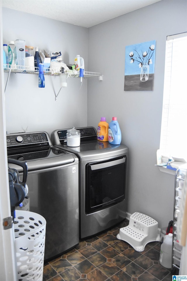 clothes washing area featuring laundry area, washer and clothes dryer, and stone finish floor