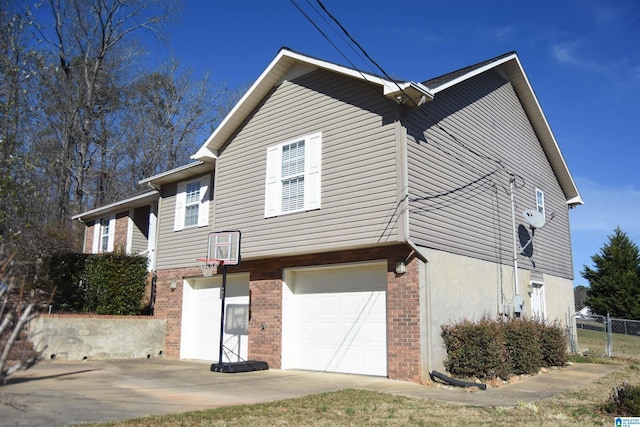 exterior space with brick siding, stucco siding, an attached garage, fence, and driveway