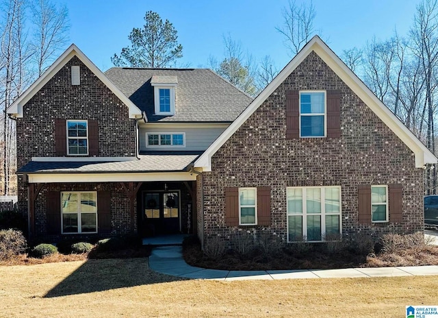 view of front facade featuring covered porch, a front yard, and brick siding