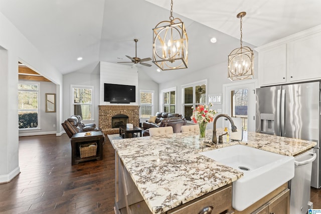 kitchen featuring a fireplace, a sink, light stone countertops, dark wood finished floors, and decorative light fixtures