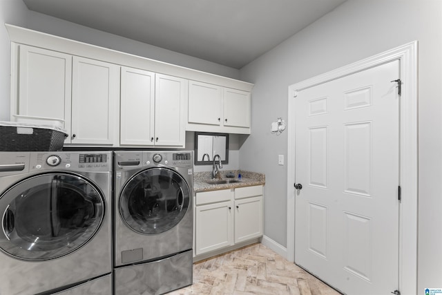 washroom featuring cabinet space, a sink, washer and clothes dryer, and baseboards