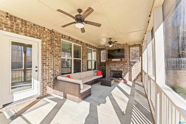 view of patio / terrace featuring ceiling fan and an outdoor living space with a fireplace