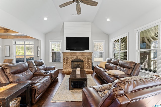 living area with lofted ceiling, ceiling fan, dark wood-style flooring, visible vents, and a brick fireplace