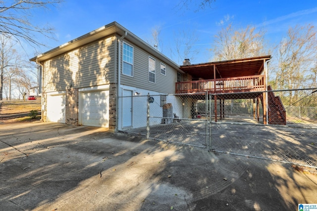 view of home's exterior with concrete driveway, an attached garage, stairs, fence, and a deck