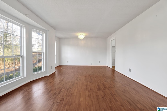 unfurnished room featuring dark wood-style floors and baseboards