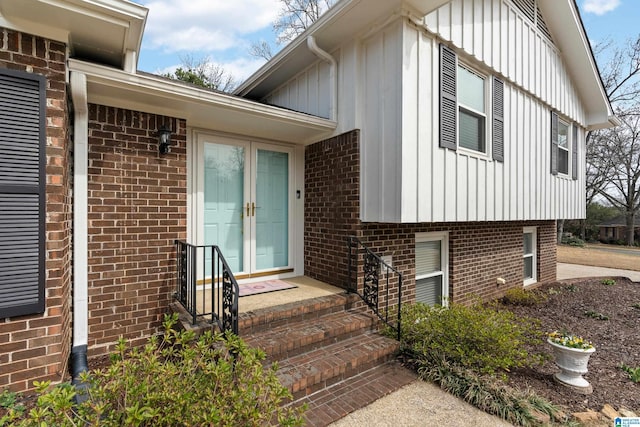 view of exterior entry featuring french doors, brick siding, and board and batten siding