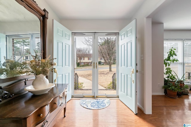 doorway with french doors, baseboards, and light wood finished floors