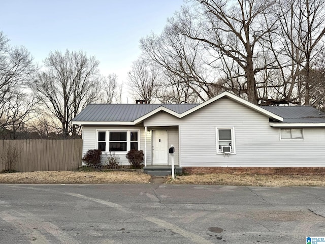 ranch-style home with metal roof and fence