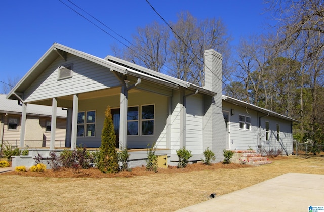 view of front of house with crawl space, a porch, a chimney, and a front yard