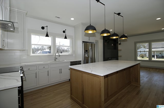 kitchen with plenty of natural light, stainless steel fridge with ice dispenser, a kitchen island, dark wood-style flooring, and a sink