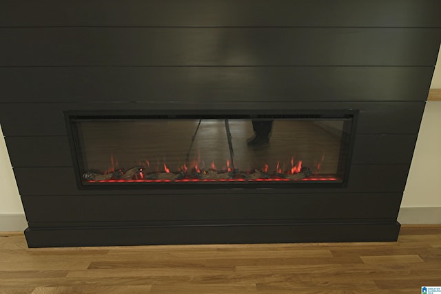 interior details featuring a warm lit fireplace and wood finished floors