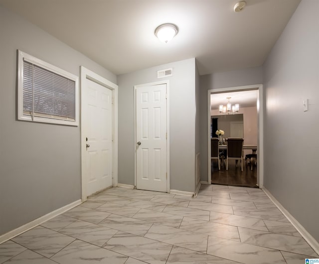 corridor with visible vents, baseboards, marble finish floor, and a chandelier