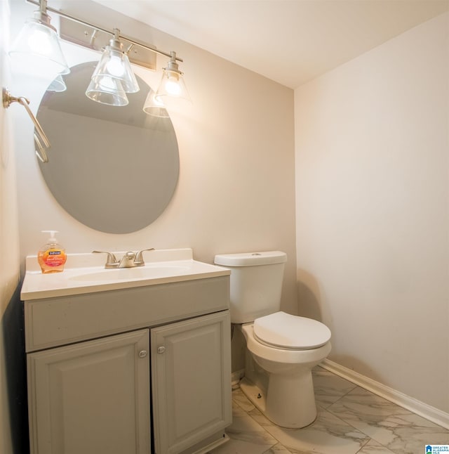 half bathroom with baseboards, toilet, marble finish floor, and vanity