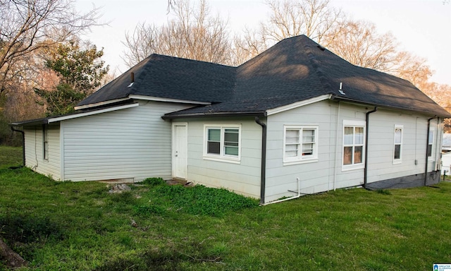 back of property featuring a yard and roof with shingles