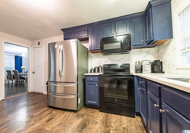 kitchen featuring wood finished floors, light stone countertops, decorative backsplash, black appliances, and blue cabinets