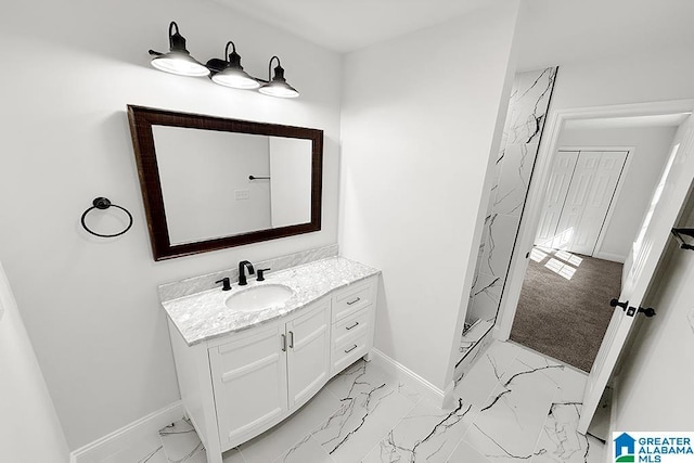 bathroom with marble finish floor, vanity, baseboards, and a shower stall