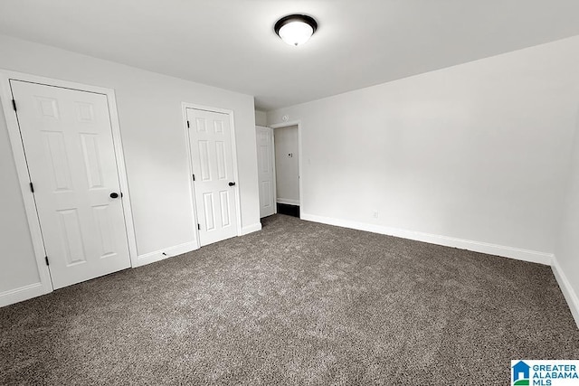 unfurnished bedroom with dark colored carpet and baseboards