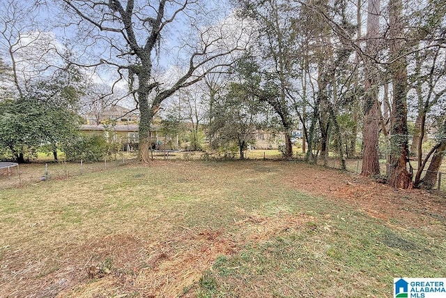 view of yard featuring a trampoline and fence