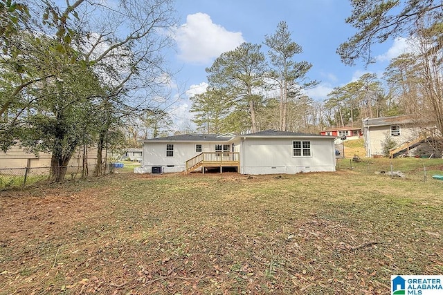 rear view of house with crawl space, fence, a deck, and a lawn