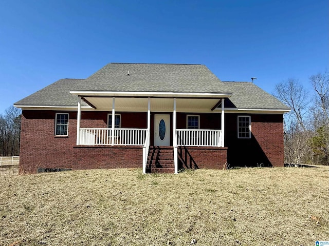 view of front of property with covered porch, brick siding, and roof with shingles