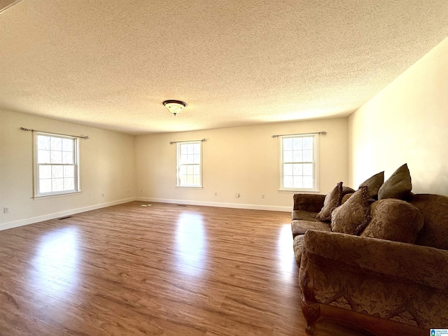 living area featuring plenty of natural light, visible vents, and wood finished floors