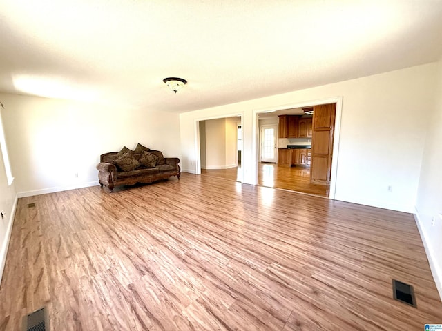 living area with light wood-style floors, baseboards, and visible vents