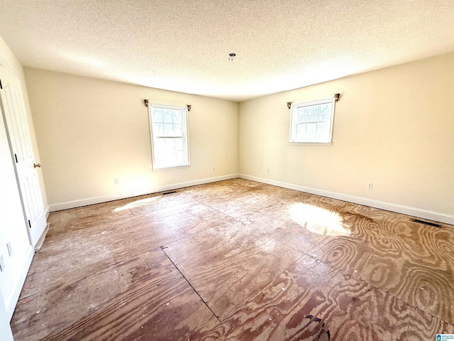 spare room with visible vents, a textured ceiling, and baseboards