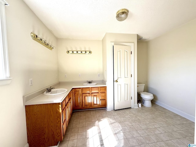 full bathroom featuring double vanity, a sink, toilet, and baseboards