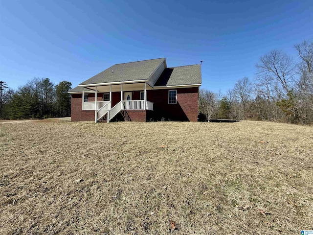 rear view of house featuring covered porch and brick siding