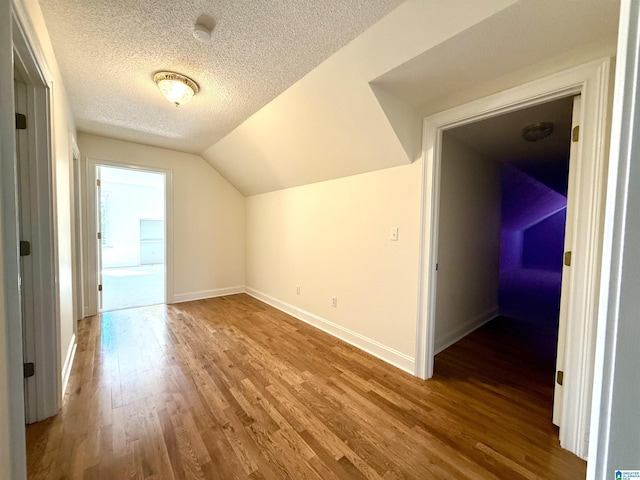 bonus room featuring lofted ceiling, a textured ceiling, baseboards, and wood finished floors