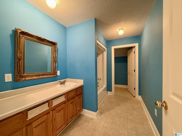 full bath featuring bathtub / shower combination, vanity, a textured ceiling, baseboards, and tile patterned floors