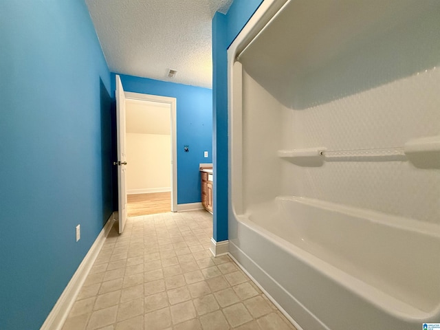 bathroom featuring tile patterned flooring, baseboards, and a textured ceiling