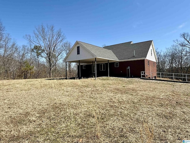 rear view of house featuring a yard and brick siding