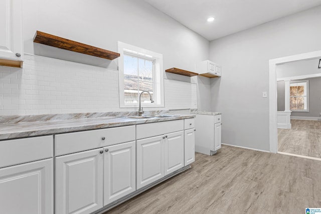 kitchen featuring a sink, light wood-style flooring, decorative backsplash, and open shelves