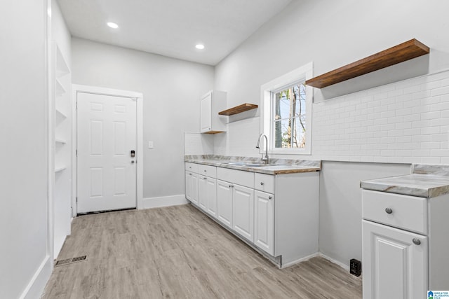 kitchen featuring white cabinetry, open shelves, a sink, and light countertops