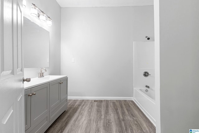 full bathroom featuring visible vents, shower / bath combination, vanity, wood finished floors, and baseboards