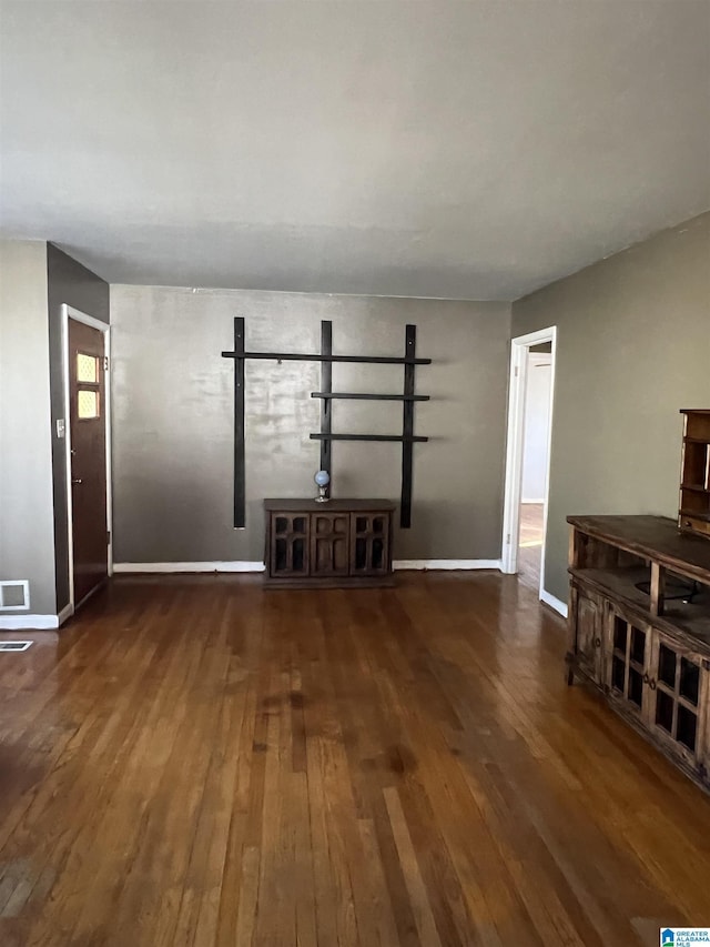 unfurnished living room with wood-type flooring, visible vents, and baseboards